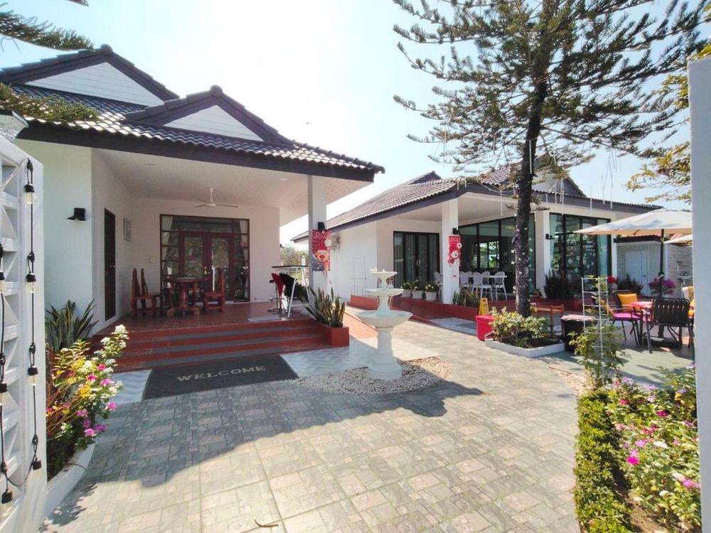 The paved front courtyard with a fountain, seating and both villa buildings