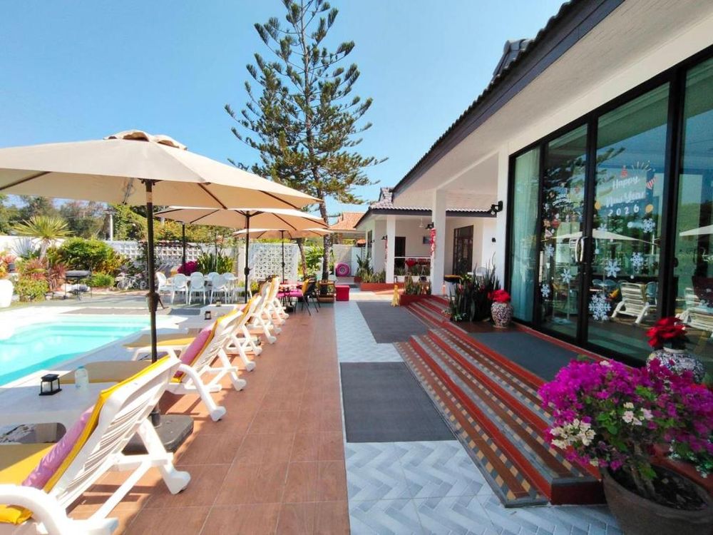 The pool with sun loungers, umbrellas and the villa behind