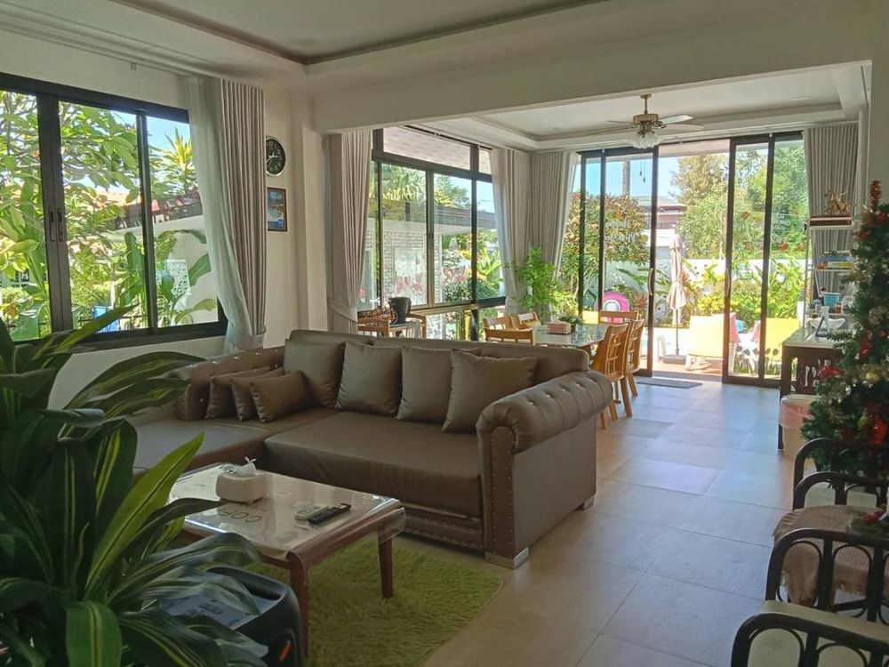 The open-plan living room with a large sofa and garden views on three sides