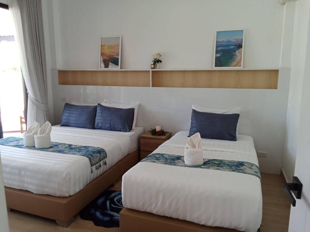A bedroom with two beds, coastal prints and a garden window
